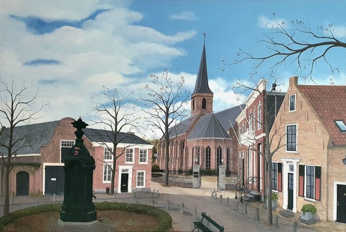 Gezicht op een dorp met een kerk, bomen en historische gebouwen onder een blauwe lucht.