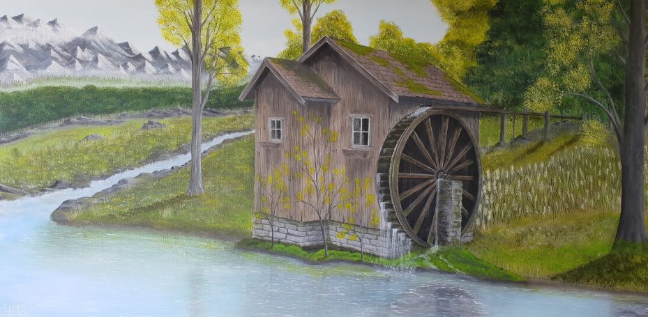 Houten watermolen aan de rand van een rivier, omgeven door bomen en groen.